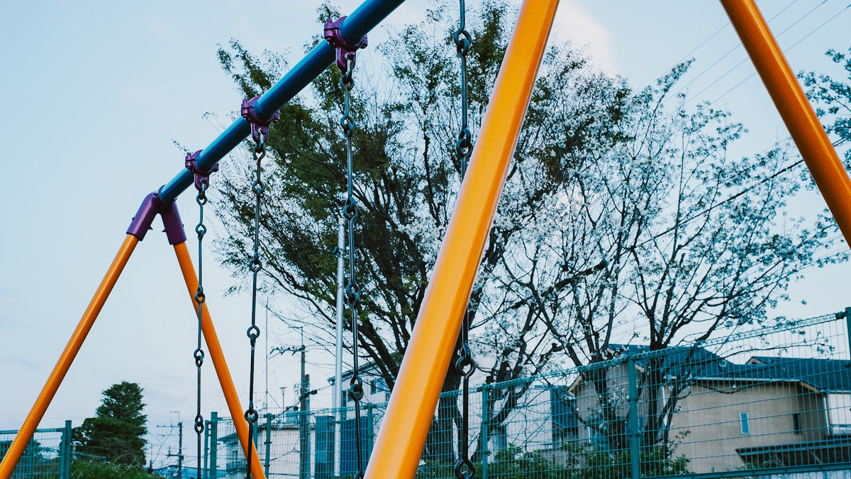Empty playground swings under a cloudy sky